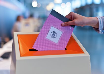 En person som putter stemmeseddel i valgboks - Klikk for stort bilete